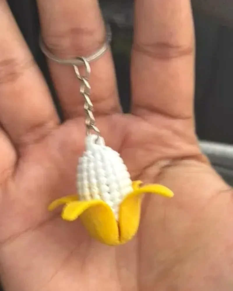 Llavero de elote con granos blancos y hojas amarillas abiertas.